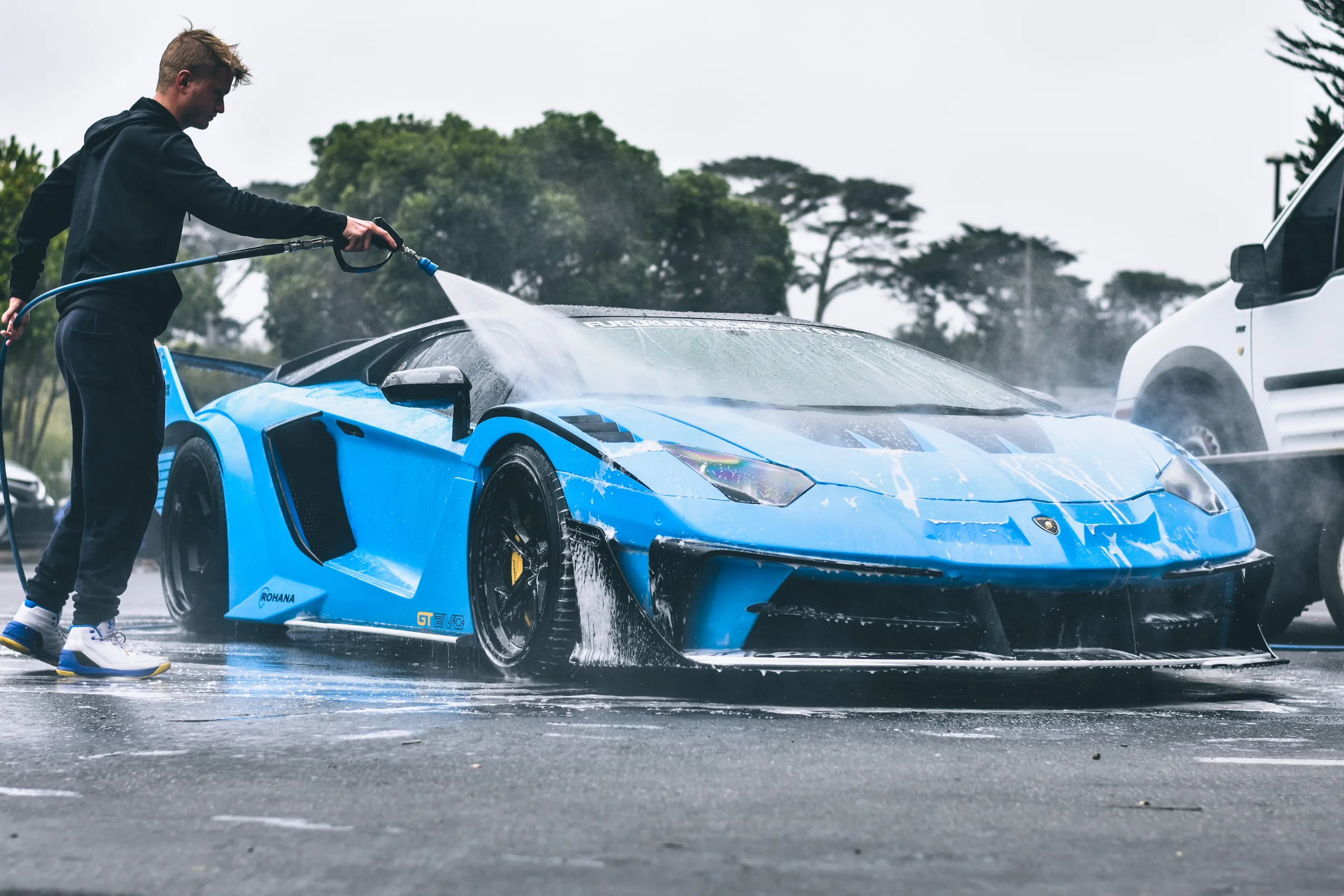 A detailer washing a bright blue sports car